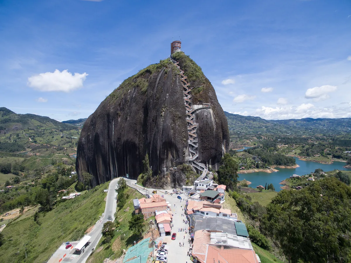 A steep staircase ascends a massive rock formation above surrounding hills