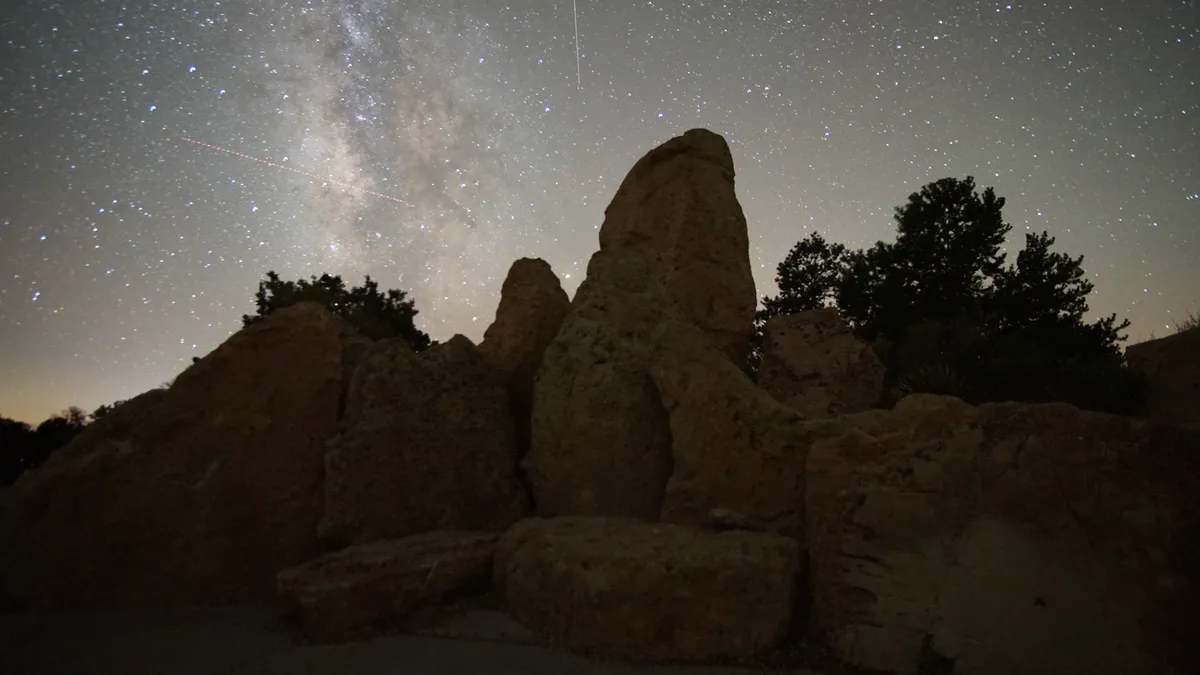 Rock formations and trees beneath a star-filled night sky