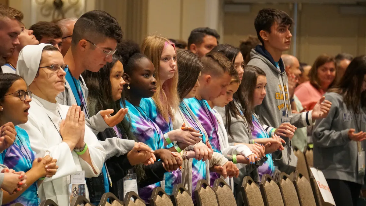 Attendees pray together with their hands raised