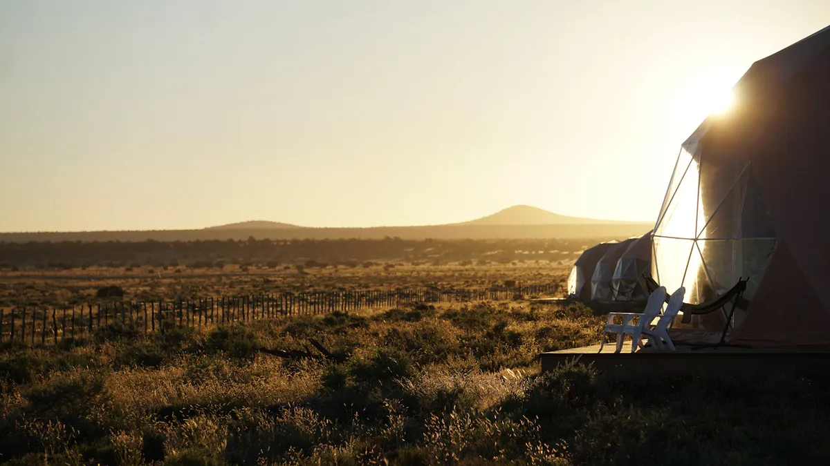 Low sunlight falls across the landscape beside a resort dome