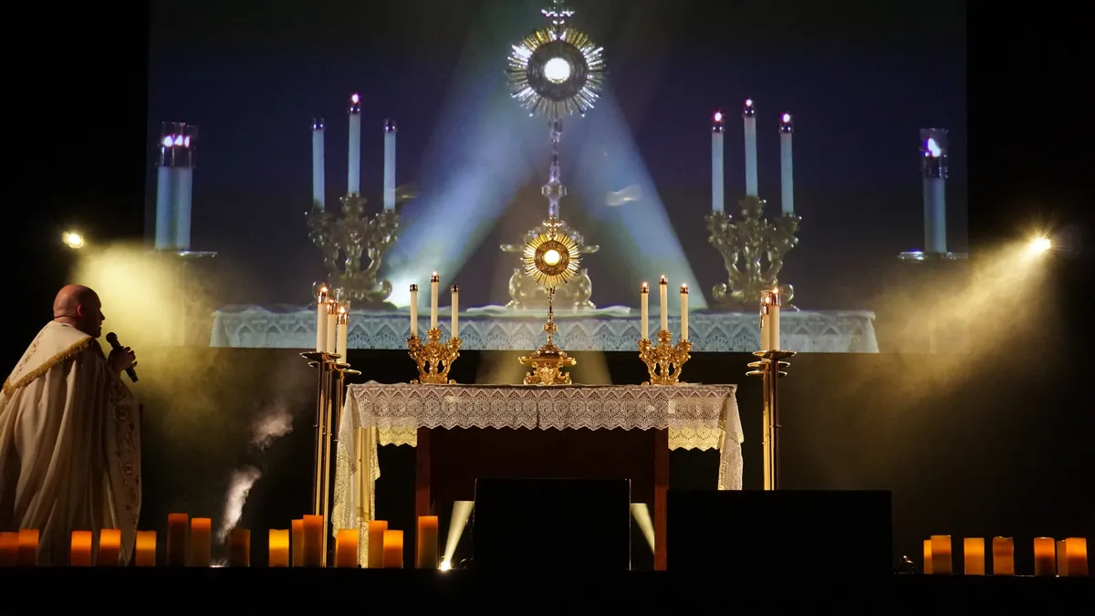 A candlelit altar and monstrance surrounded by stage lighting