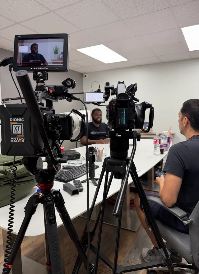 Behind the scenes: multiple cameras and a monitor framing an interview